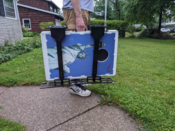 Caddy hangs on cornhole set for easy carrying  side  view